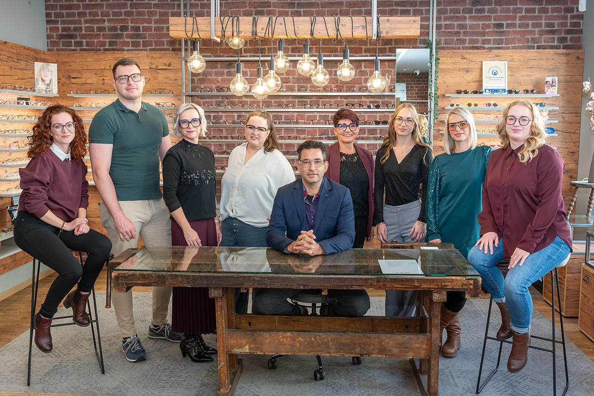 Das Team von Paul Unger Augenoptik & Hörakustik vor der Brillenwand im Geschäft